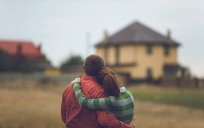 Man and woman hugging outside a home