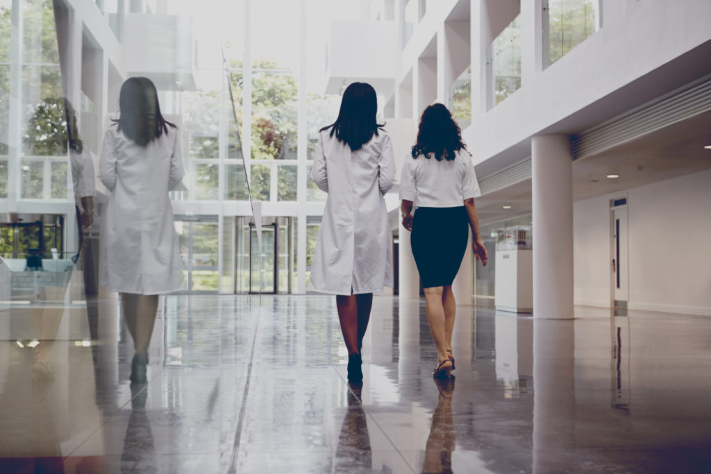 a medical student and resident walking in the corridors of hospital discussing their programs