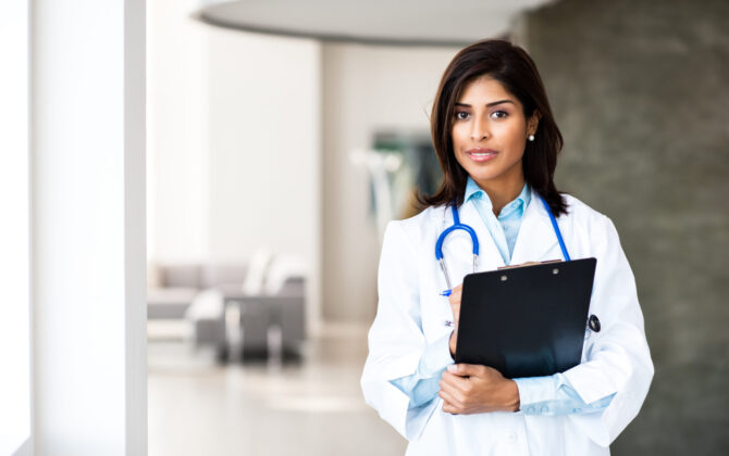 a young female doctor with notepad in hand and blue stethoscope over her shoulder,Physician’s Guide to Managing Medical Student Loans