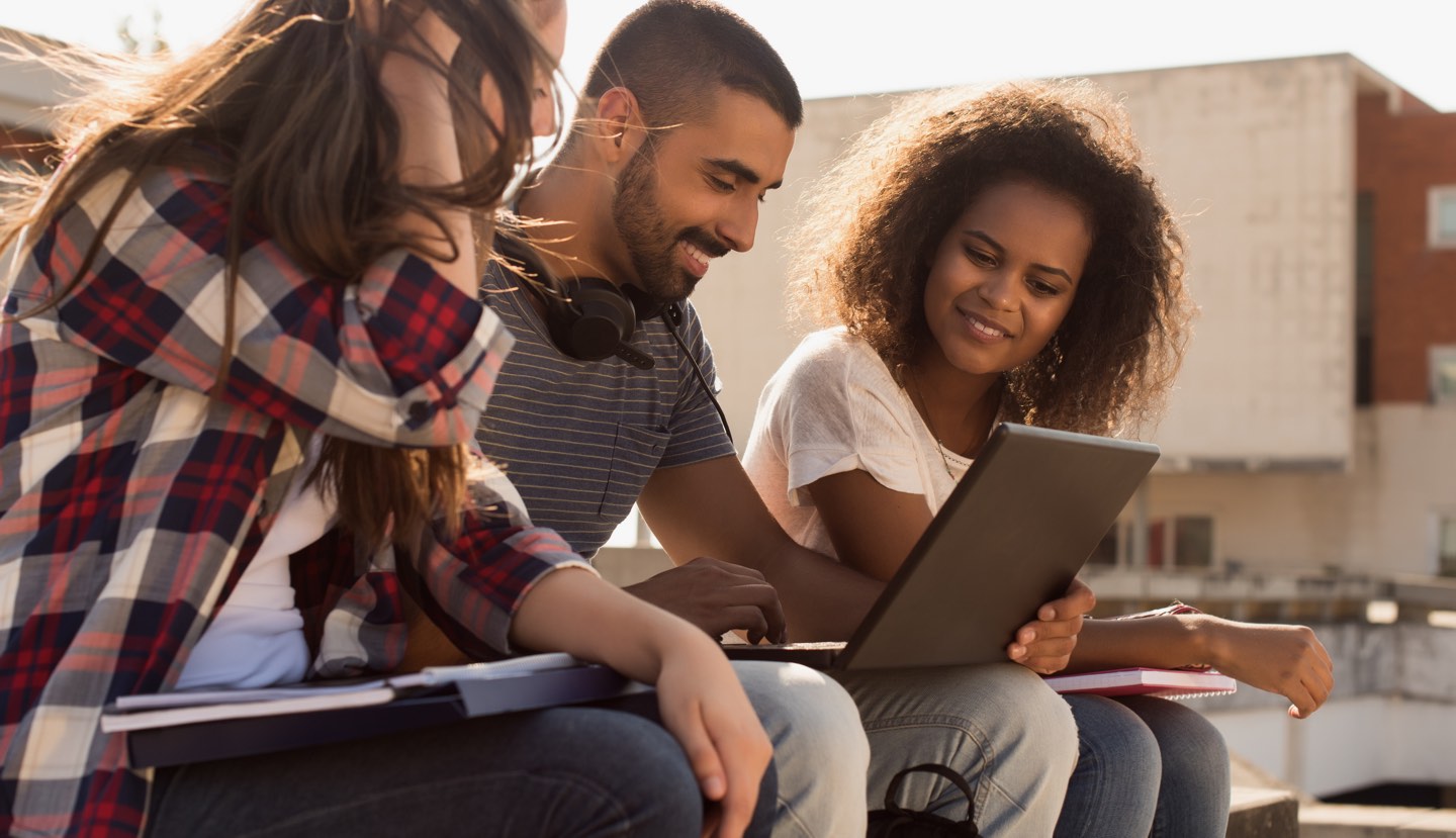 three students sitting outside and look at one's laptop, understand the different types of student loan repayment options