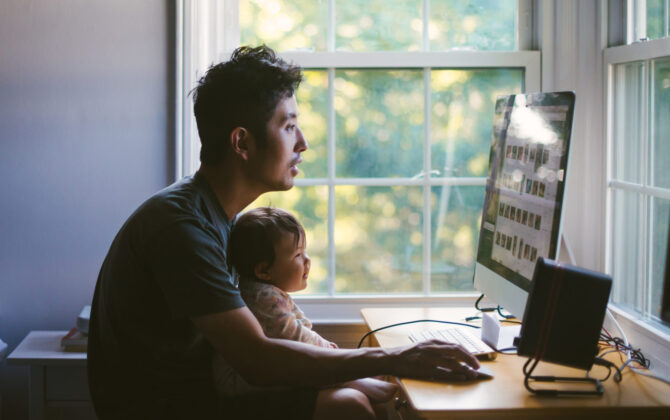 Father on desktop computer with child on his lap