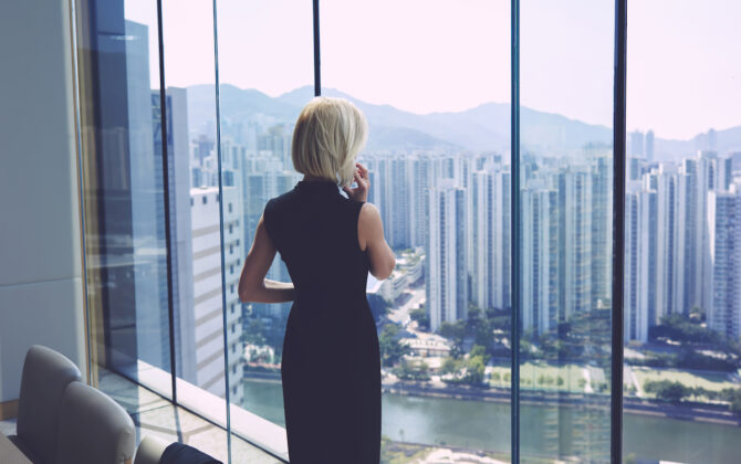 A young female professional looking at a skyline out a window.