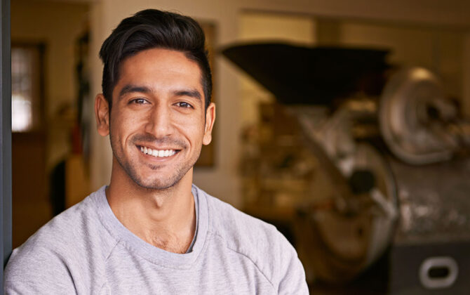 A smiling young man wearing a grey t-shirt