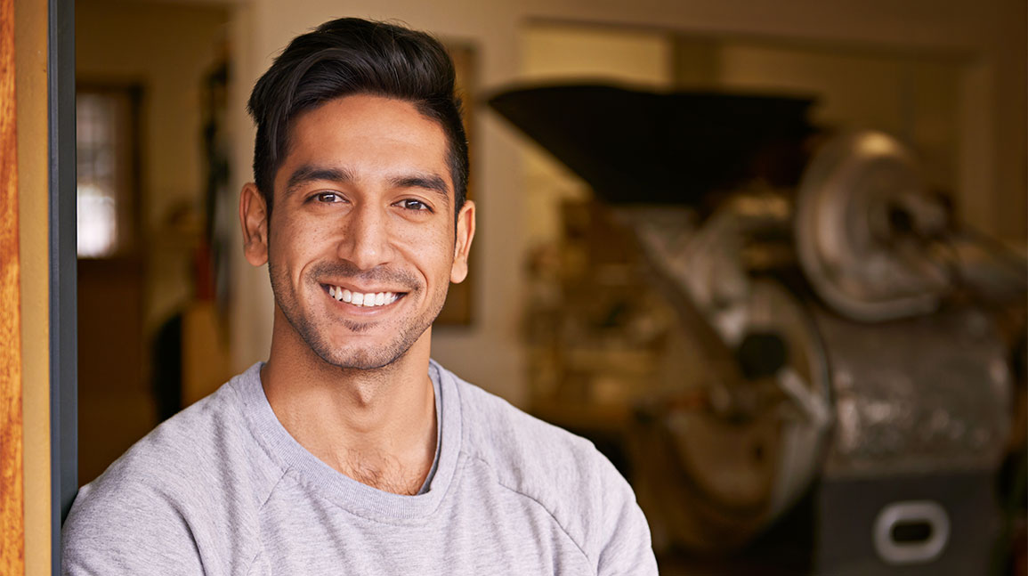 A smiling young man wearing a grey t-shirt