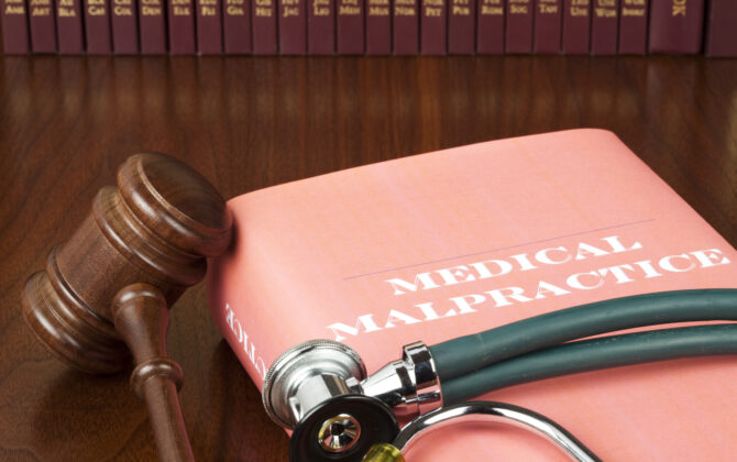 medical malpractice book, wooden hammer and stethoscope on table