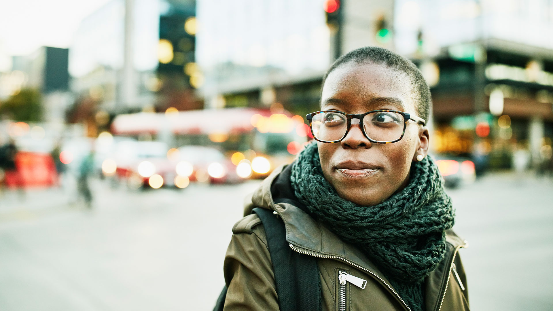 College student with glasses walking through the city, thinking about how to pay off student loan.