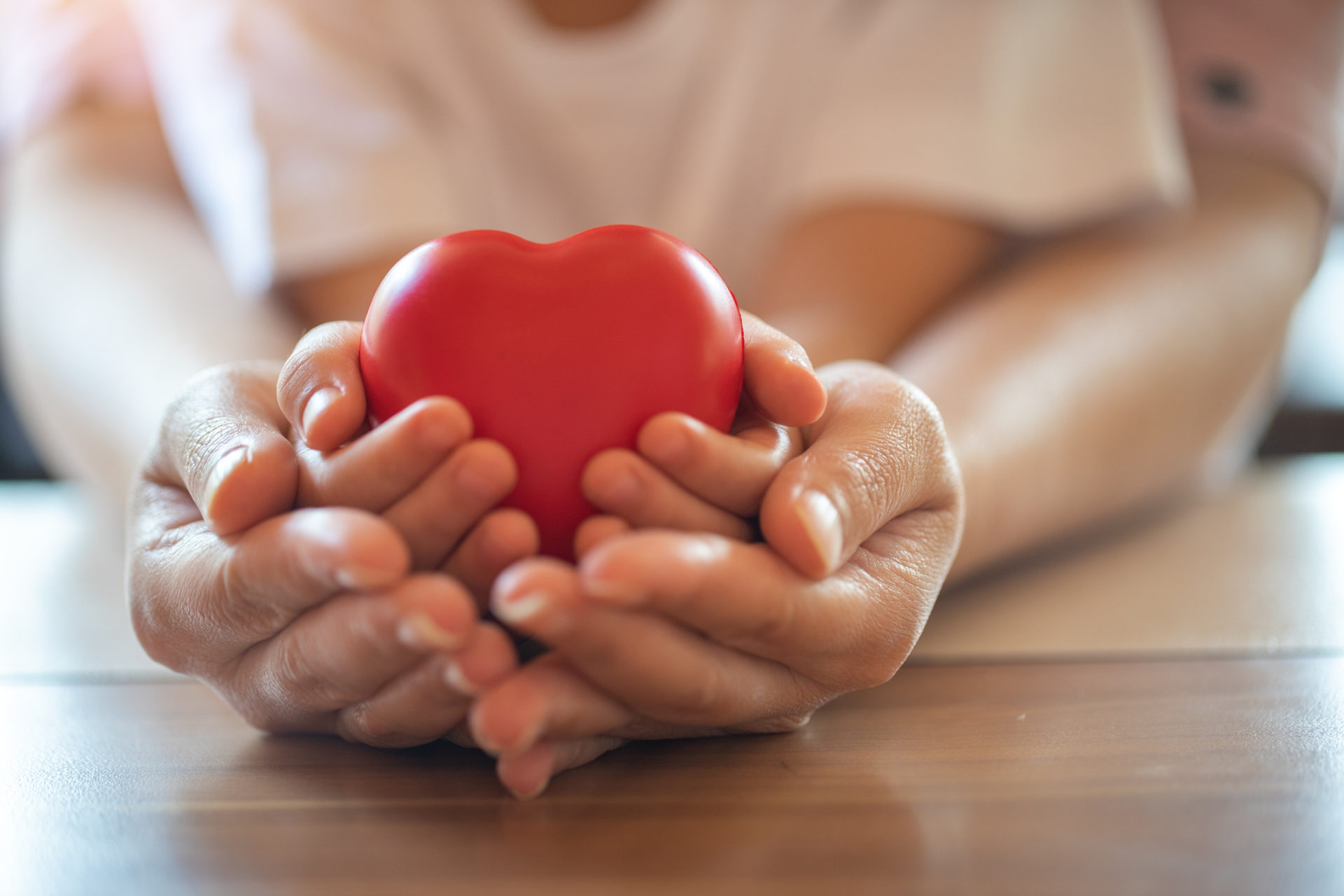 adult and child hands holding red heart.