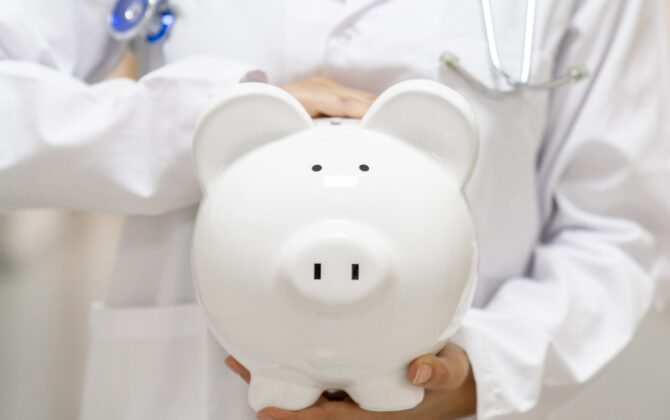 Doctor holding a white piggybank at the hospital.