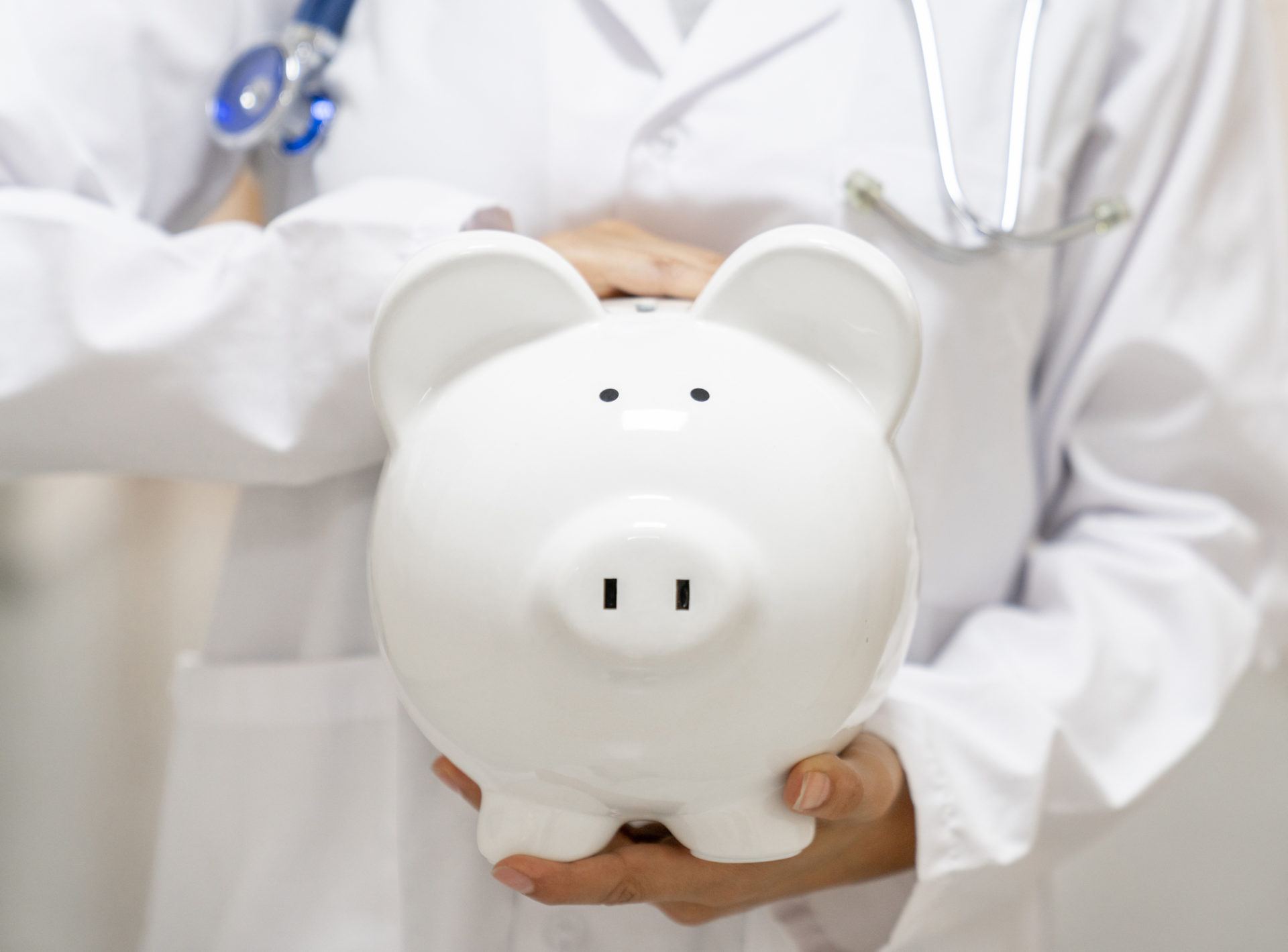 Doctor holding a white piggybank at the hospital.