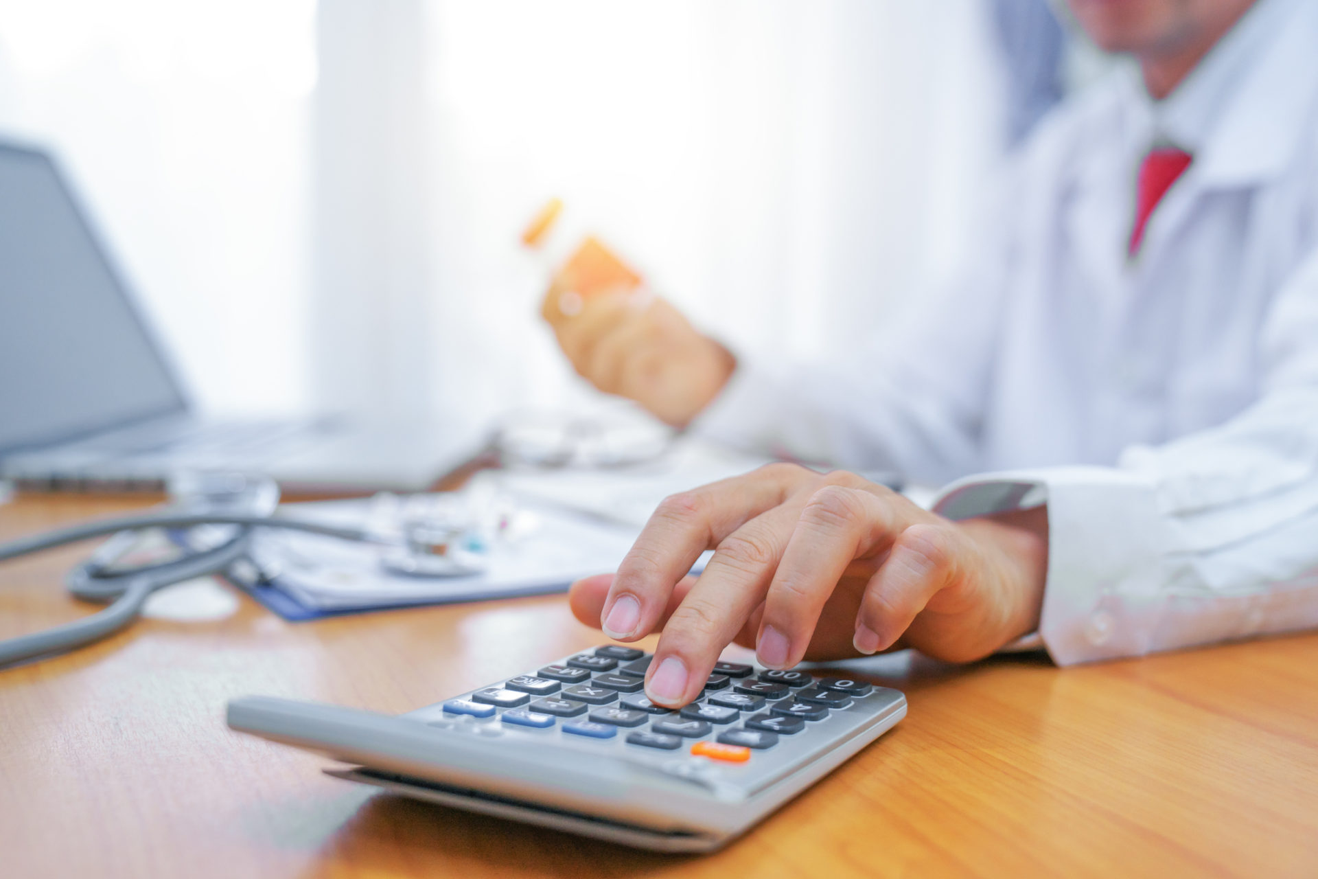 A doctor creating a budget by using a calculator and notebook.