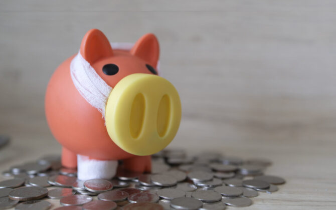 Red color piggy bank on top of coins showing the importance of saving money and financial planning