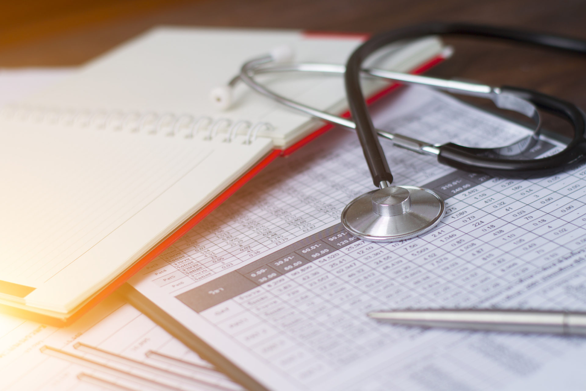 Stethoscope sitting on charts and a notebook.