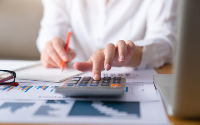 Woman with notes and calculator calculating the payoff of student loans.