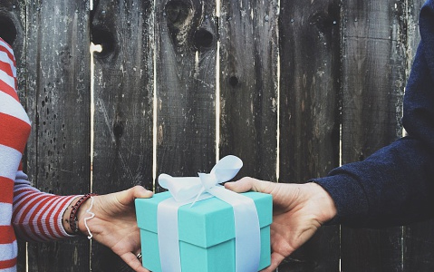 A man gifting a present to a woman.