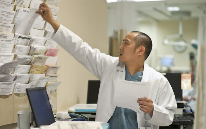 Doctor reaching for a patient's chart in a hospital.