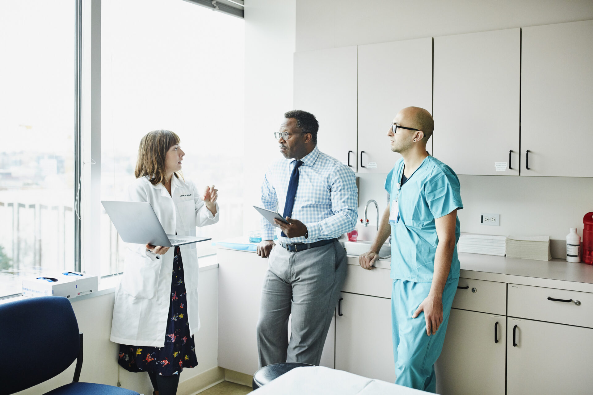 Female doctor leading medical team discussion in hospital exam room