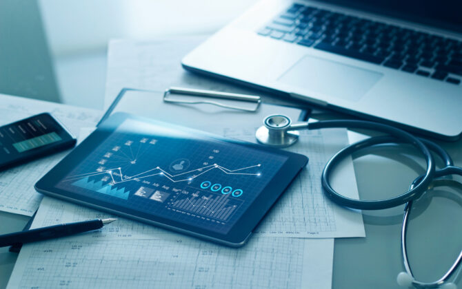 Laptop, stethoscope, tablet displaying medical information.