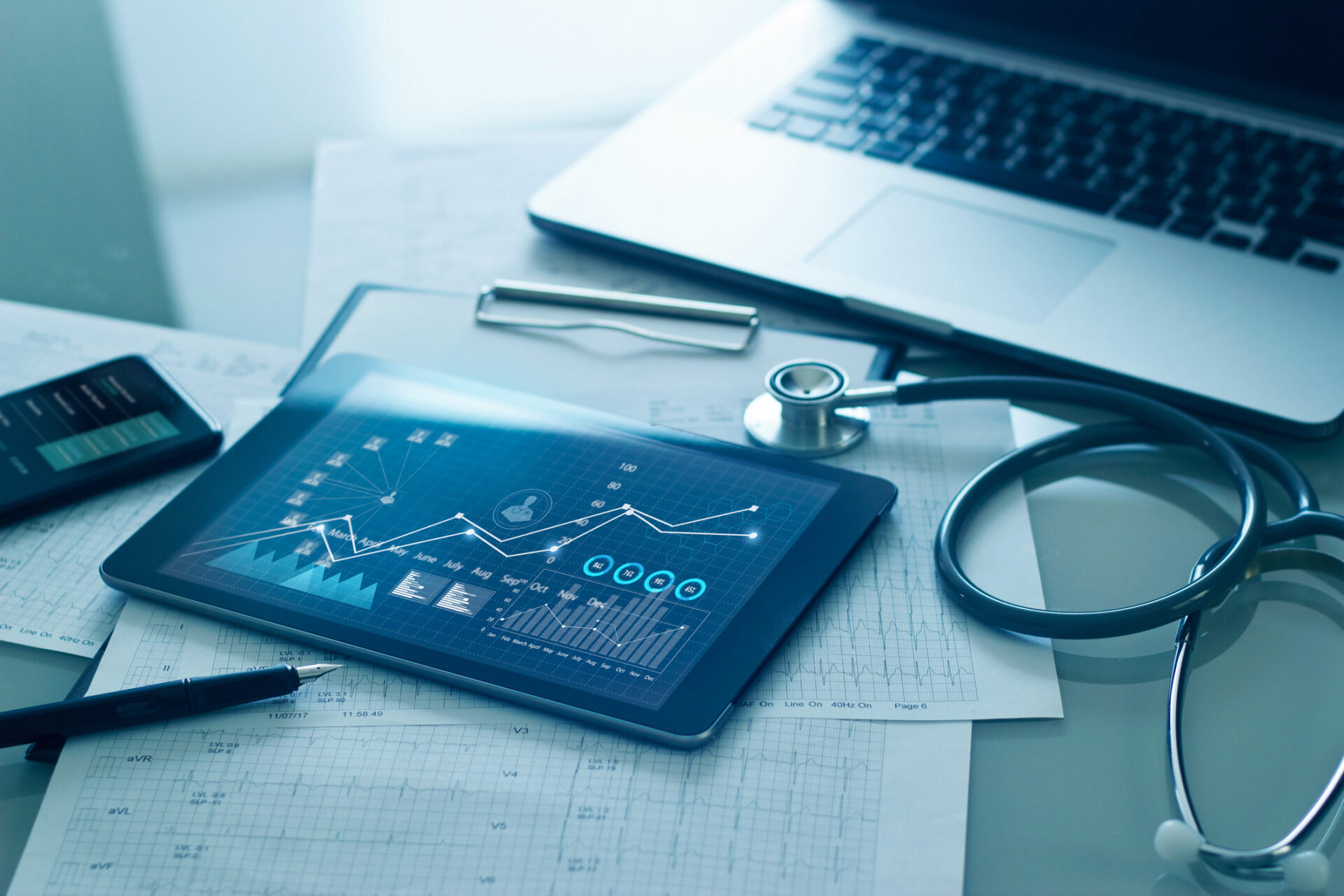 Laptop, stethoscope, tablet displaying medical information.