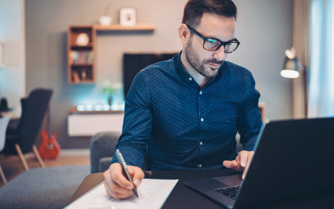 Businessman using laptop and doing paperwork at home