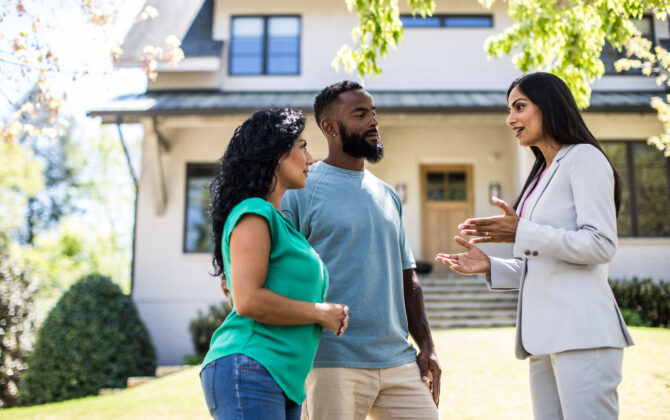 Couple meeting with real estate agent in front of home