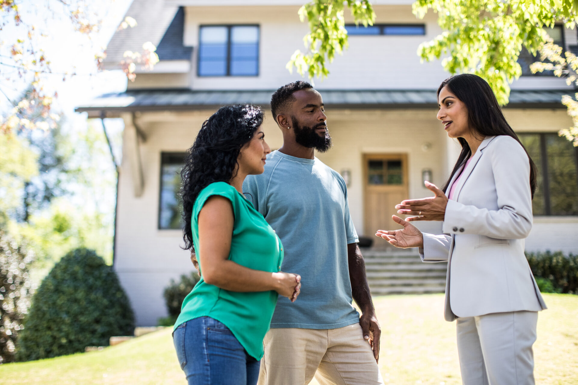 Couple meeting with real estate agent in front of home