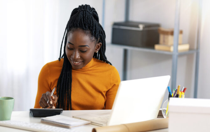 Close up of one African American woman using calculator, calculating finance at home.