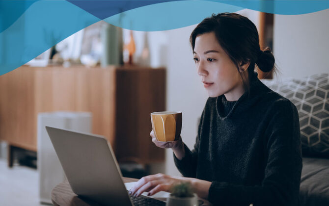 Young woman drinking coffee and reading on her laptop