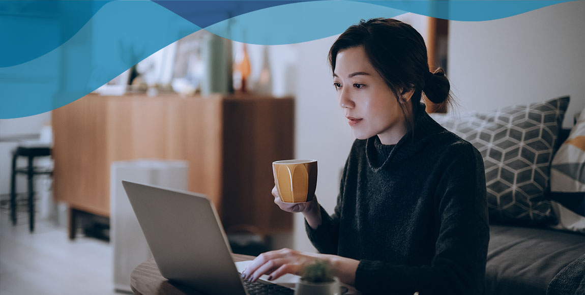 Young woman drinking coffee and reading on her laptop