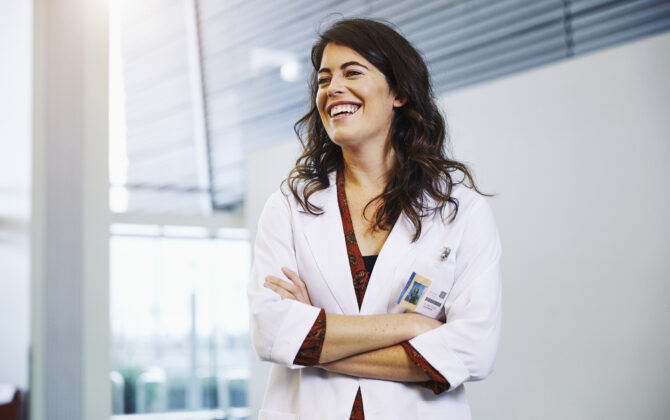 Female physician laughing with arms crossed.