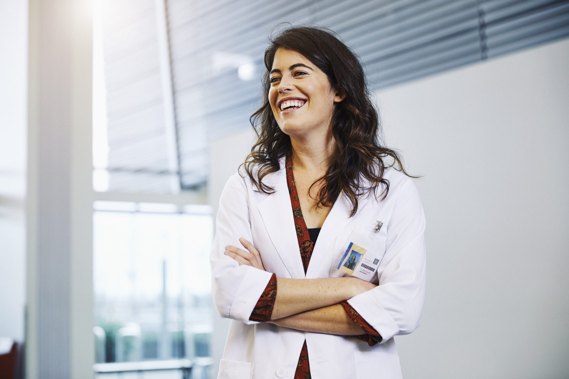 Female physician laughing with arms crossed.