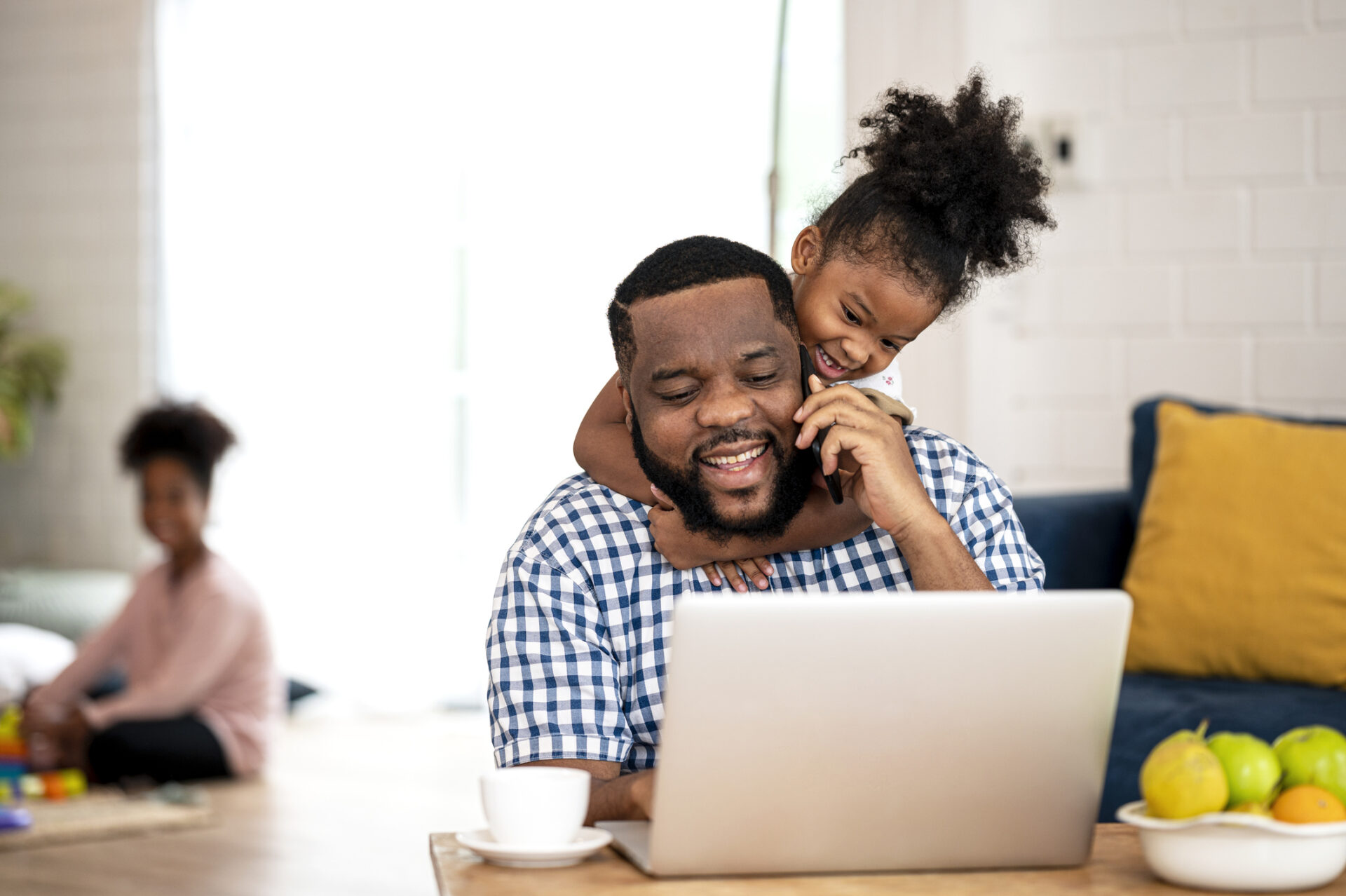 Papa please play with me!. A African Father working from home, talking on call while cute little daughter disturb her father to stop working.