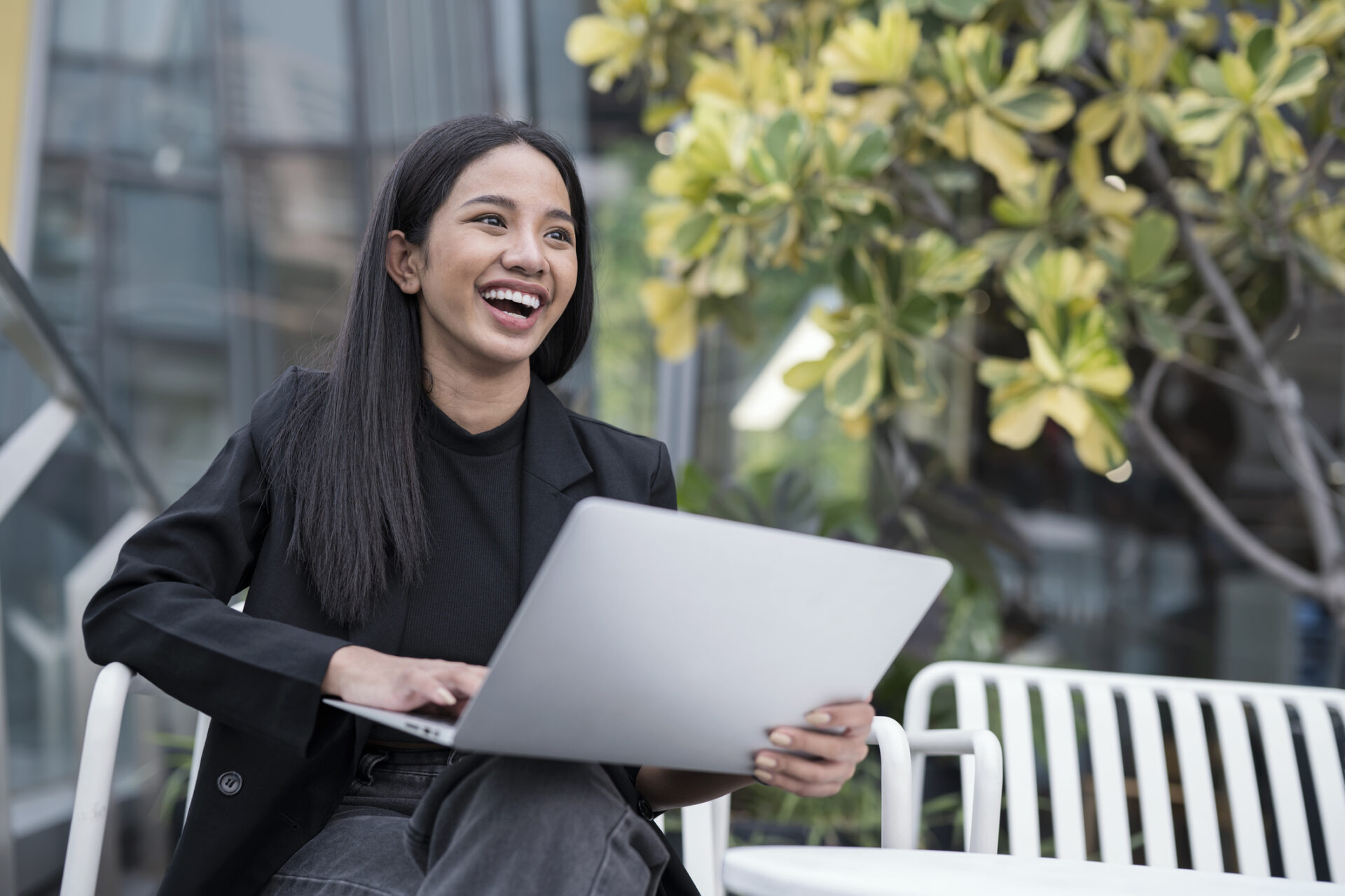 Shift Negative Thoughts Into a Positive Mindset for Creative Thinking in Young Business Entrepreneurs. Shot of Young Businesswomen is laughing while working on a laptop to discussion with her team outside the business office.