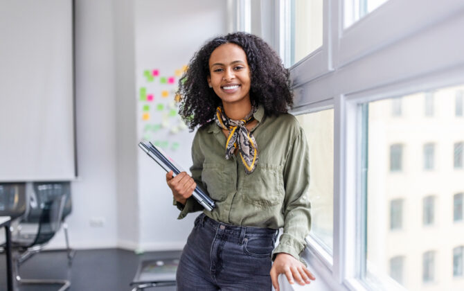 Girl standing and smiling near a window after Applying for a Checking Account with Direct Deposit Bonuses