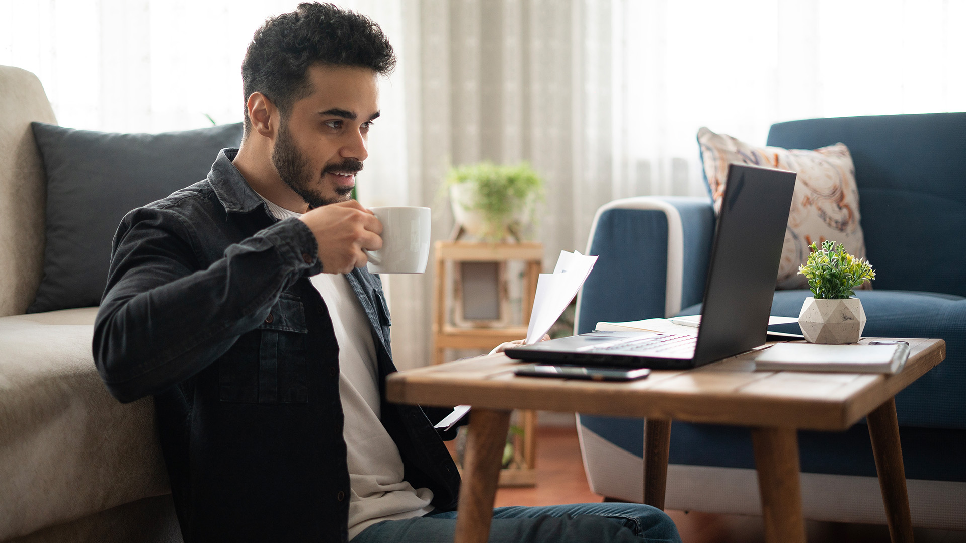 A man drinking coffee and learning more about Income-Based Repayment (IBR) to manage his student loans on a laptop.
