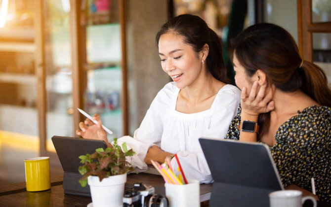 Two women checking if their refinanced student loans are eligible for forgiveness.