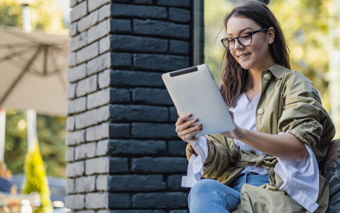 Woman outside reading tablet learning about student loan forgiveness through income-driven repayment