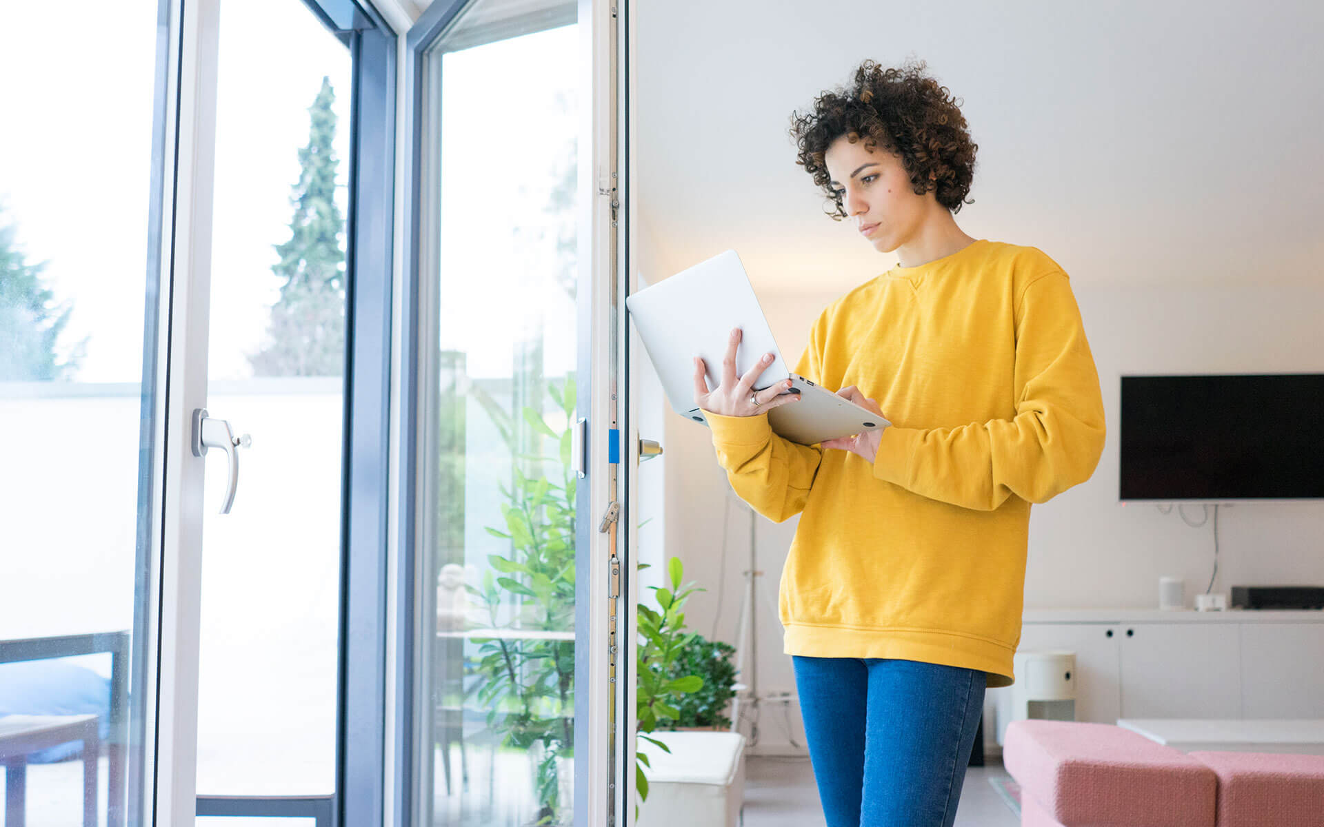 A young woman gazes at her laptop, studying when to pay off student loans.