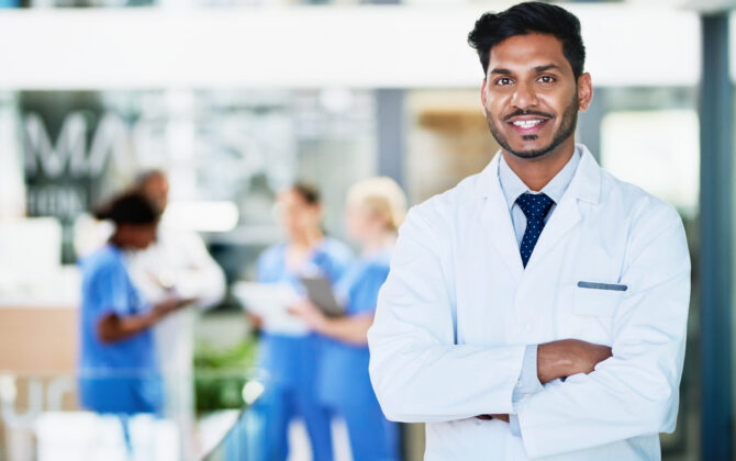 Portrait of a healthcare worker standing in a hospital with colleagues in the background