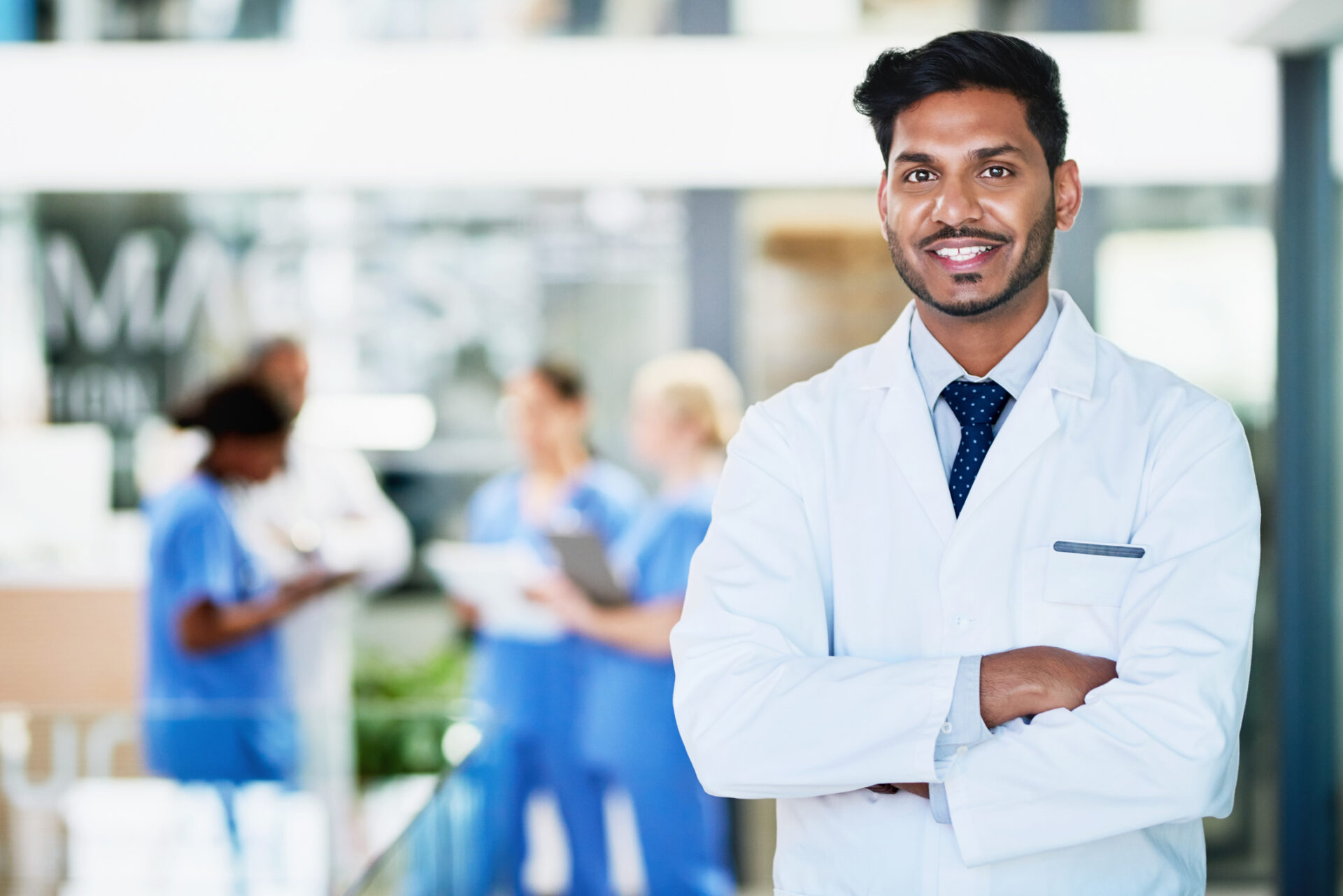 Portrait of a healthcare worker standing in a hospital with colleagues in the background