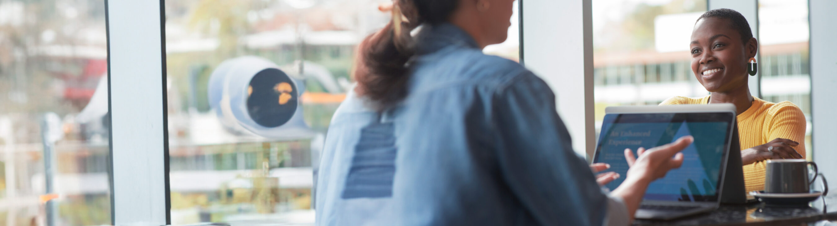 A professional woman in a workspace is discussing student loan forgiveness with a colleague.